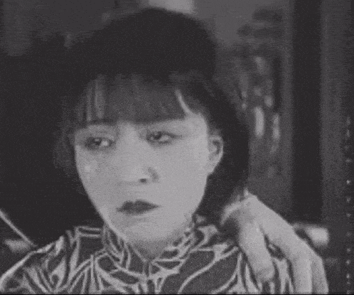 a black and white photo of a woman with a man 's arm on her shoulder .