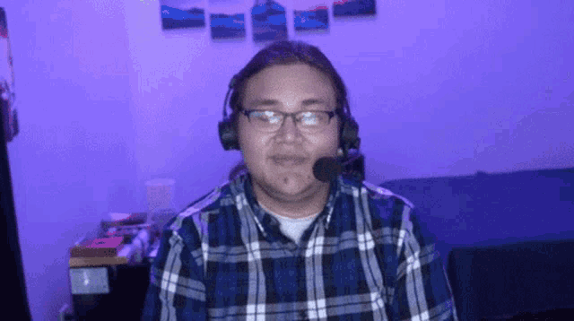 a man wearing a plaid shirt and headphones with a microphone on his head