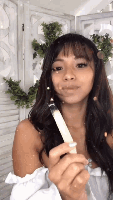 a woman in a white dress is holding a stick in her hands