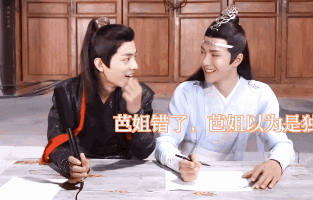 two men sitting at a table with chinese writing on it