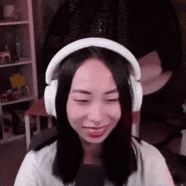 a woman wearing headphones and a microphone is smiling while sitting in front of a microphone .