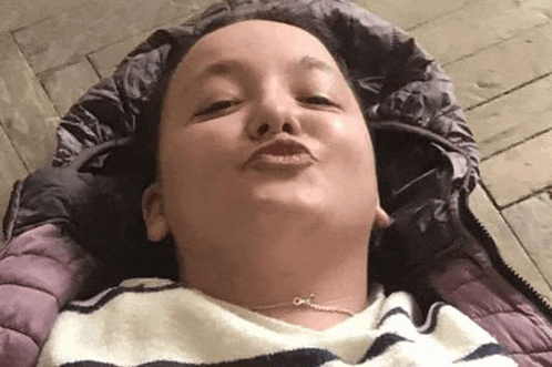 a woman is laying on the floor in a sleeping bag and making a face .