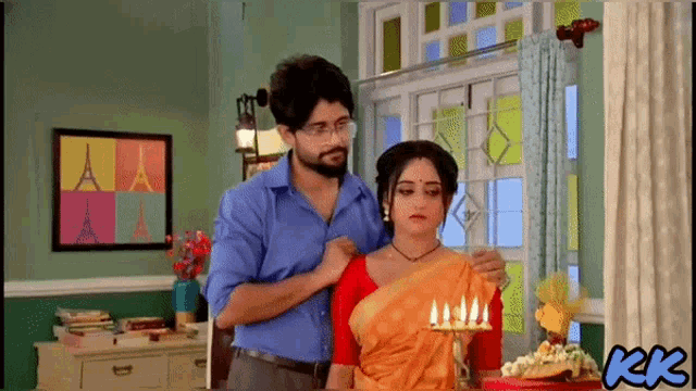 a man and a woman are standing in front of a candle holder with candles on it
