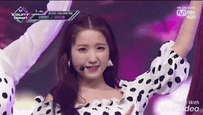 a woman in a polka dot dress is singing into a microphone on stage .