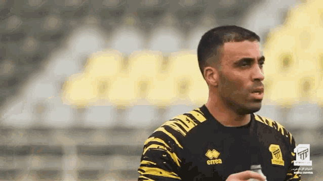 a man wearing a black and yellow errea shirt