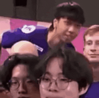 a group of people are sitting in a stadium watching a game and one of them is wearing glasses .
