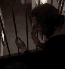 a woman is standing on a set of stairs in the dark holding onto a railing .