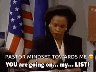 a woman in a suit is sitting at a desk in front of an american flag and talking on a cell phone .