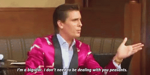 a man in a pink jacket and tie is talking to another man .