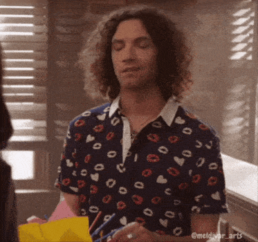 a man with curly hair wearing a shirt with kisses and hearts on it
