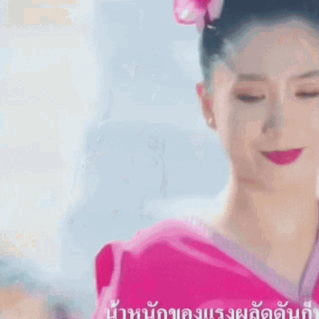 a woman in a pink dress with a flower in her hair is smiling