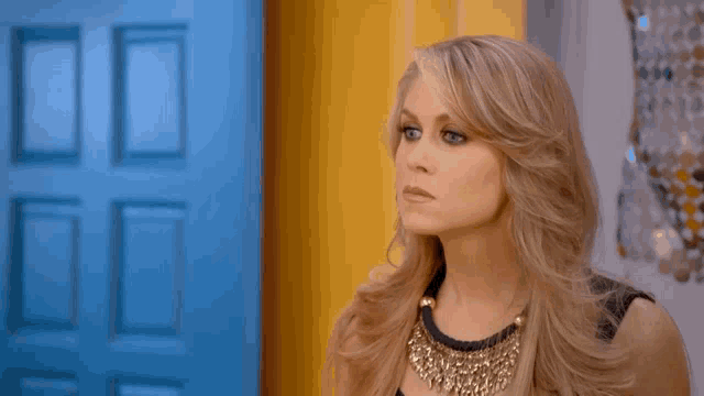 a woman is standing in front of a blue door and looking at the camera