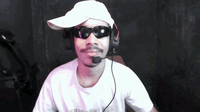 a man wearing a white hat and sunglasses with a microphone