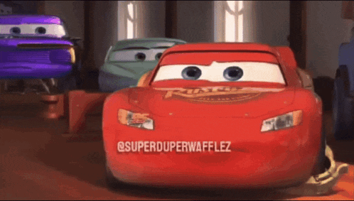 a red lightning mcqueen from the movie cars is standing in a room with other cars .
