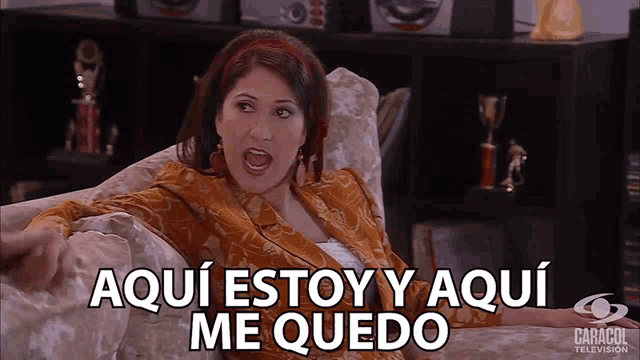 a woman sits on a couch with the words aqui estoy y aqui me quedo written on the bottom