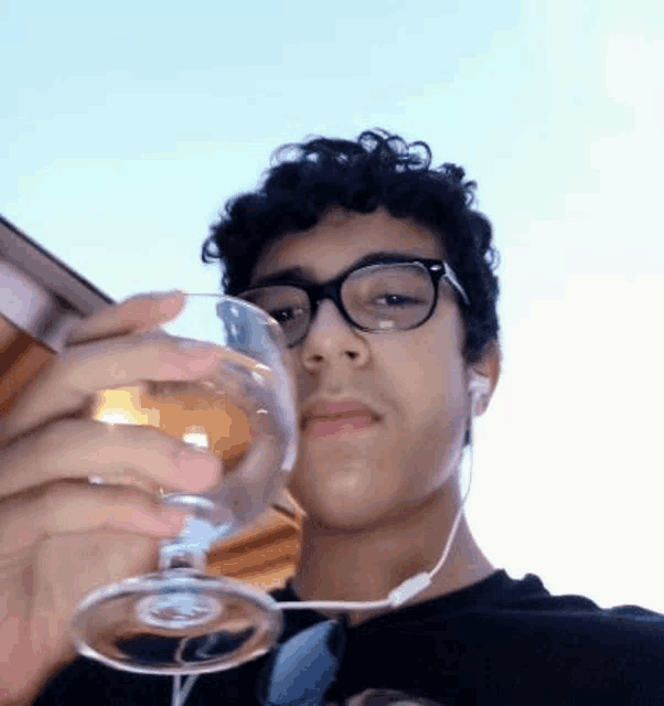 a young man with glasses is holding a glass of wine
