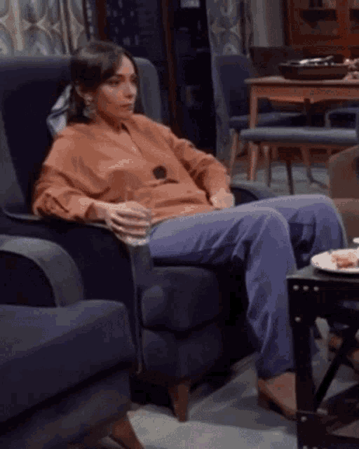 a woman is sitting in a chair with a glass of water in her hand