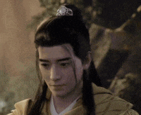 a man with long hair and a crown on his head is wearing a yellow jacket .