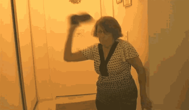 a woman in a polka dot shirt is holding a black object