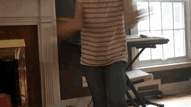 a man in a striped shirt is dancing in front of a piano