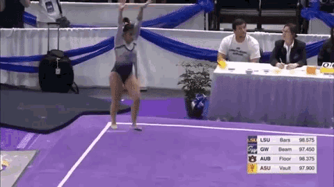 a female gymnast performs on a purple mat with a scoreboard that says lsu bars and aub floor