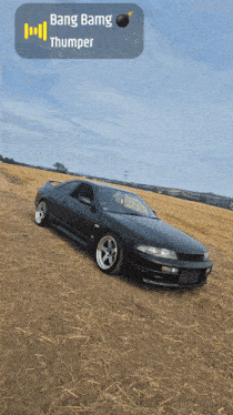 a black car is parked in the middle of a field with bang bamg thumper written above it