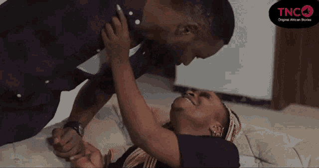 a man and a woman are laying on a couch and the man is kissing the woman on the forehead .