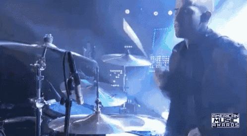 a man playing drums in front of a microphone that says american music awards