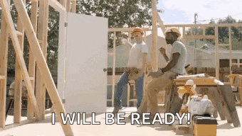 a couple of construction workers are sitting on a stool in front of a house under construction .