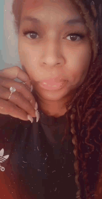 a woman with a ring on her finger is wearing an adidas shirt