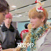 a man wearing a christmas hat and tinsel is talking to another man