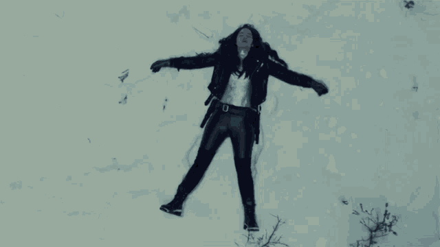 a woman is laying on her back in the snow with her arms outstretched