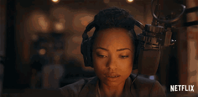 a woman wearing headphones stands in front of a microphone with a netflix logo in the background