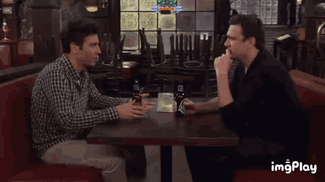 two men are sitting at a table in a restaurant with empty chairs behind them and a sign that says coca cola on it
