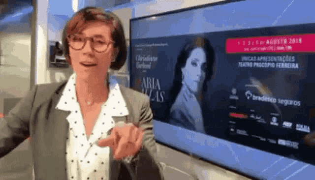 a woman stands in front of a large screen that says aria