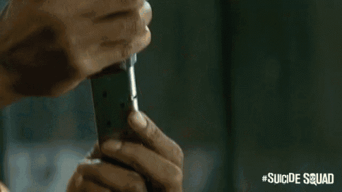 a man is pointing a gun at the camera in a scene from suicide squad .