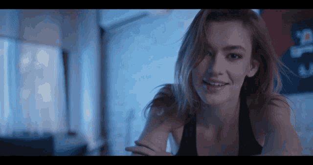 a woman in a black tank top is smiling for the camera