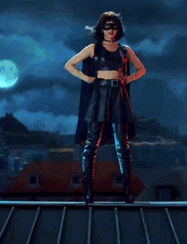 a woman in a superhero costume is standing on a roof