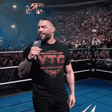a man wearing a shirt that says ytc is standing in a wrestling ring