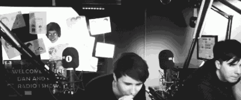 a black and white photo of two men sitting in front of microphones in a radio studio .