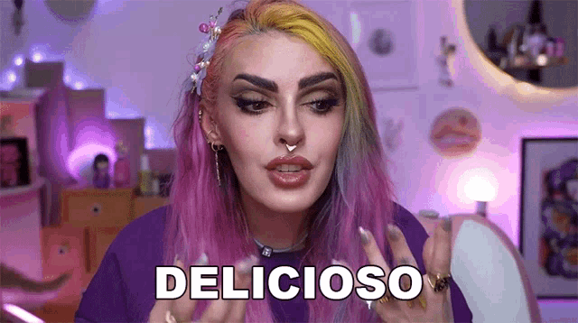 a woman with pink hair and a nose ring is making a funny face and saying " delicioso "