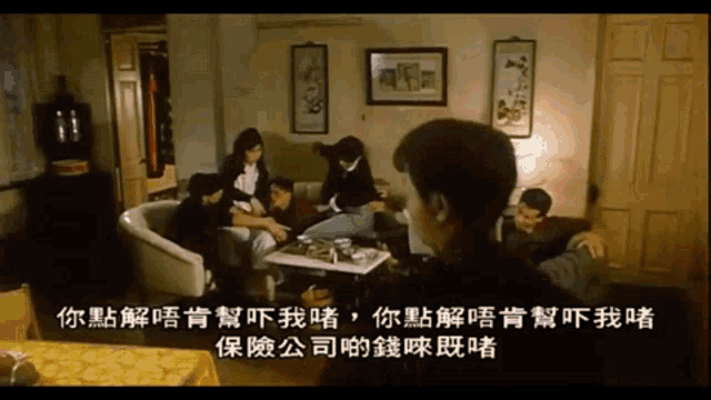 a group of people sitting around a table in a living room with chinese writing