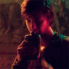 a man is holding a gun in his hand in a dark room with a red light behind him .