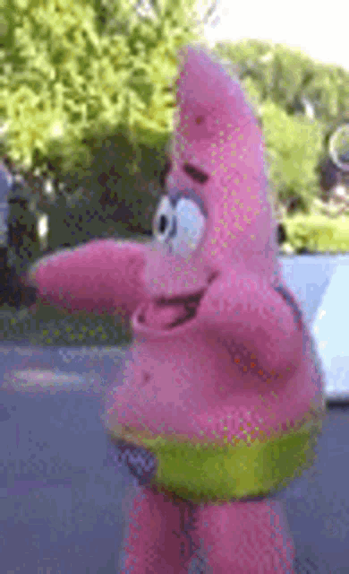 a stuffed animal of patrick star from spongebob squarepants is standing on the street .