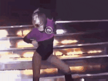 a woman is dancing on a stage in a purple and black outfit .
