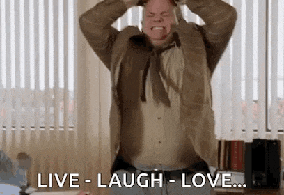 a man in a suit and tie is holding his head while laughing and saying live laugh love .