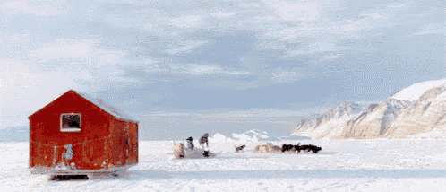 a red house is in the middle of a snow covered field
