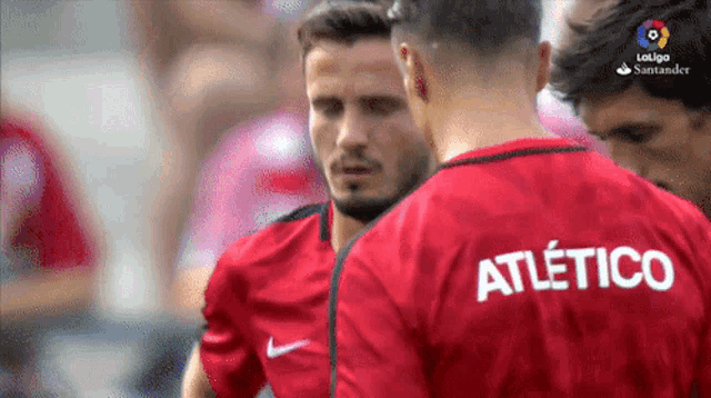 a man wearing a red shirt that says atletico on it