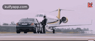 a man is standing next to a private jet and a car .