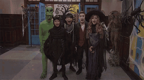 a group of people dressed up in halloween costumes are standing in a hallway